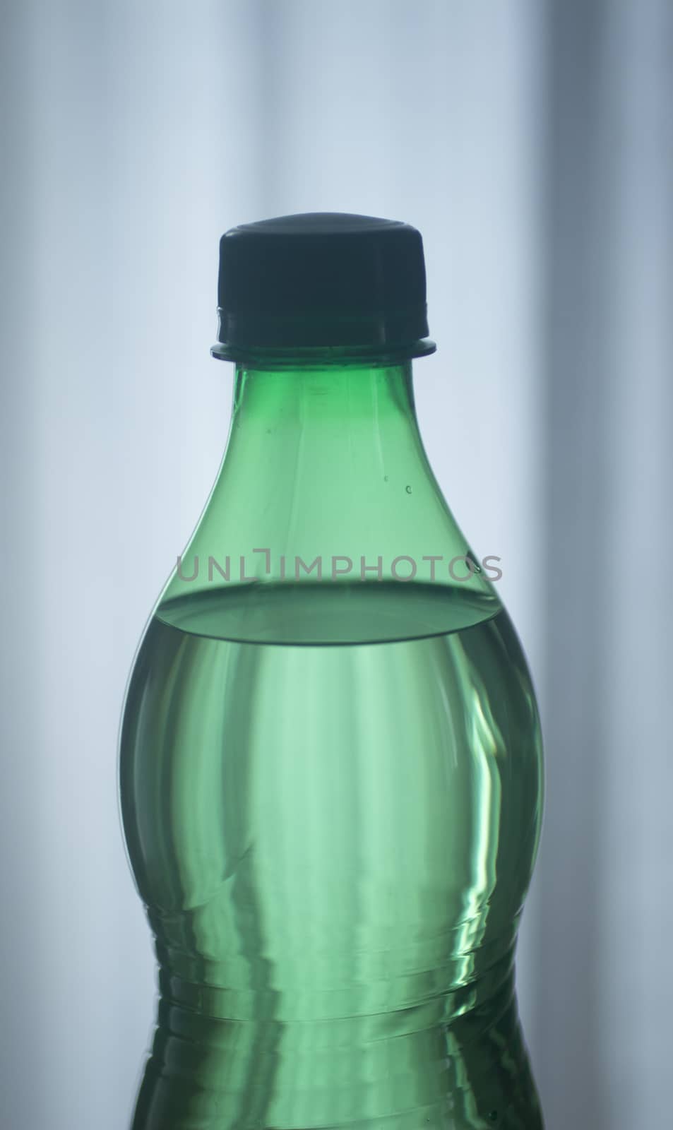Isolated plastic water bottle on a plain blue studio background close-up photo.