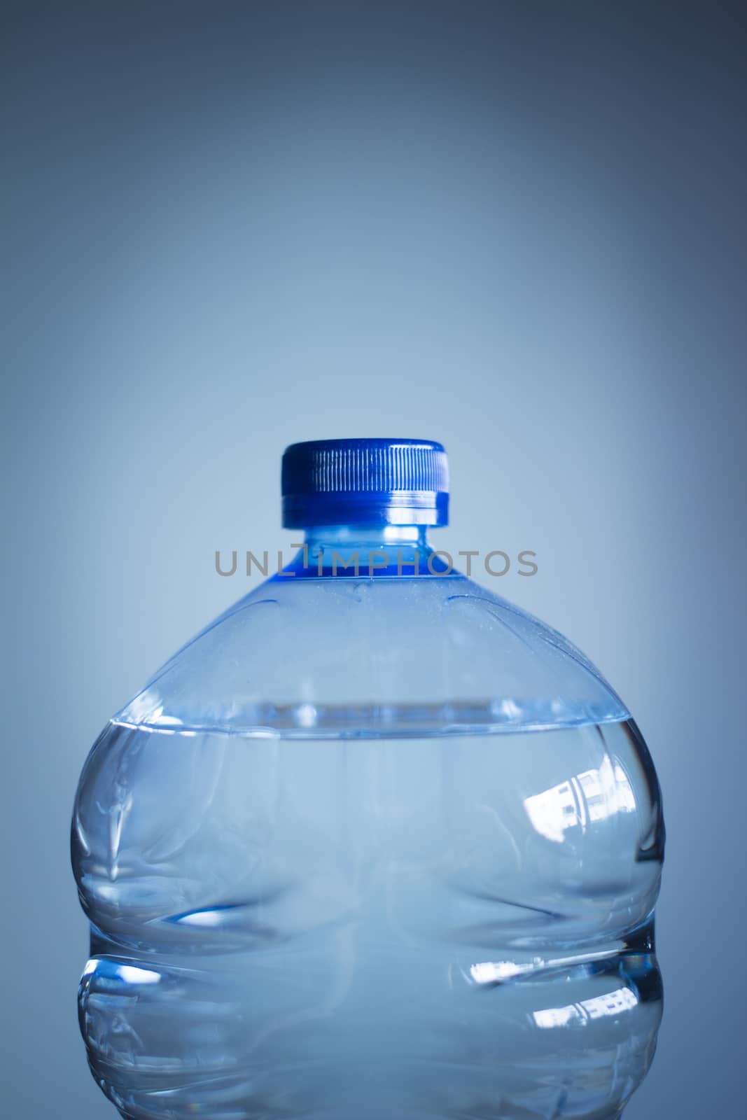 Isolated plastic water bottle on a plain blue studio background close-up photo. 