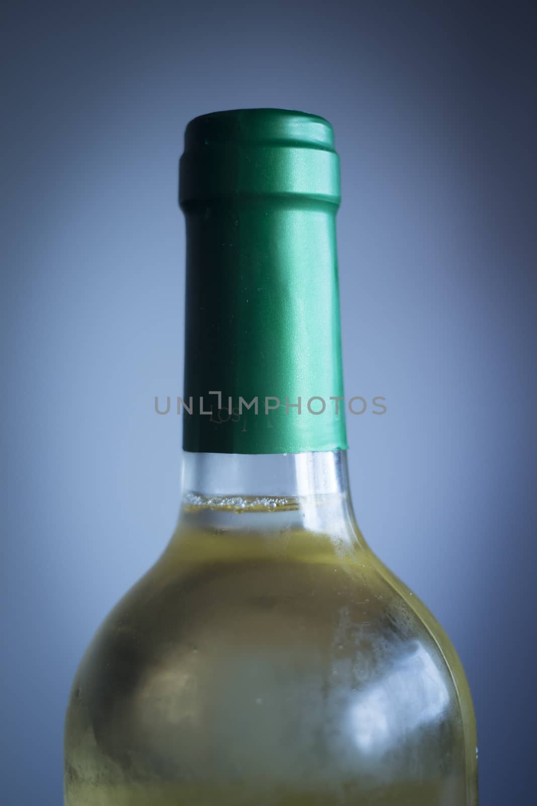 White wine bottle studio isolated close-up on plain blue background color photo.