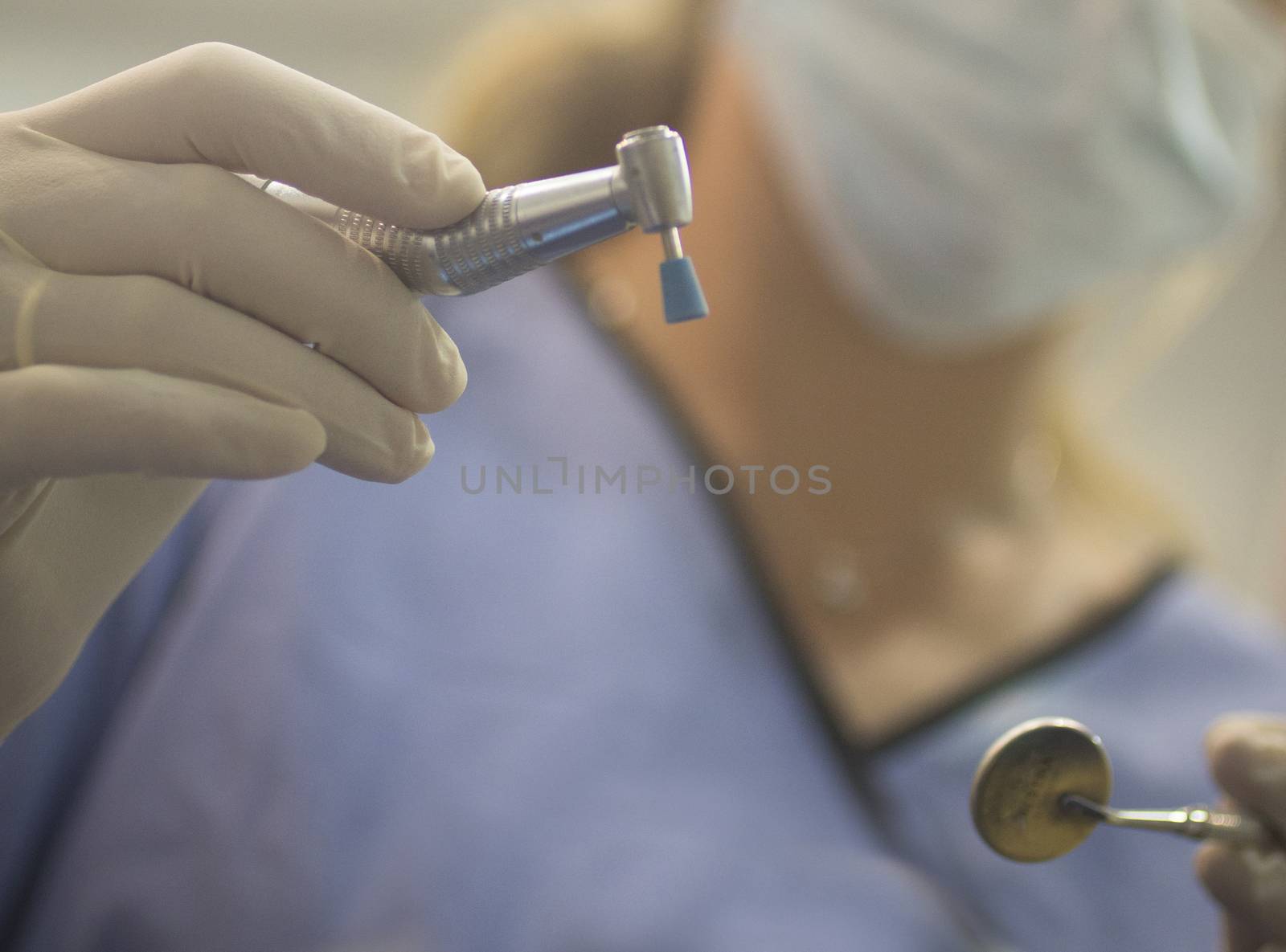 Dental instrumentation dentist pick tooth dental cleaning tool in the hand of dentist wearing face mask in dentists surgery clinic artistic color photo with shallow depth of focus.