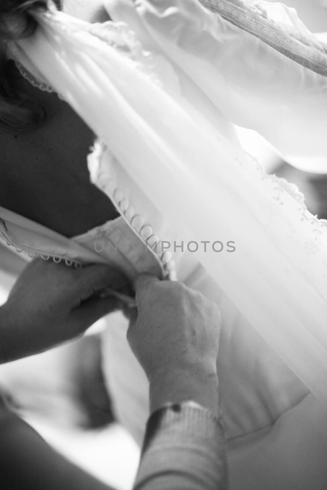Bride gets help dressing white wedding dress by edwardolive