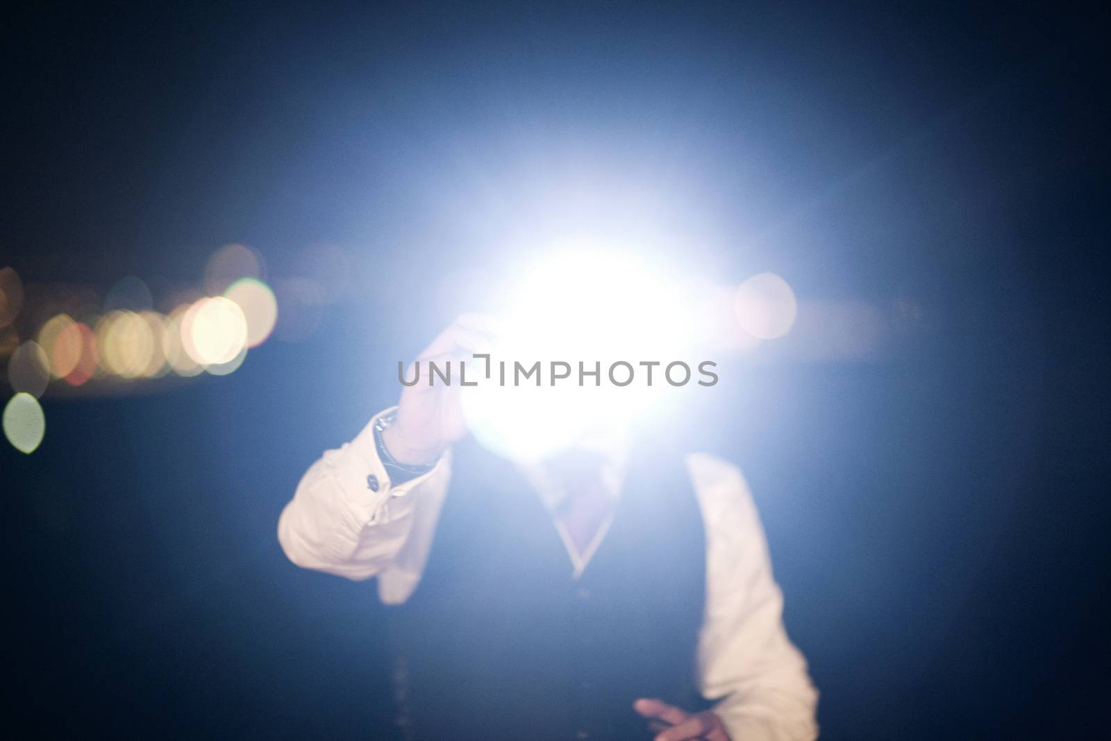 Color artistic digital rectangular horizontal photo of hand of man in dark suit and white shirt in night time wedding banquet marriage party holding camera taking a photo with flash in Barcelona Spain. Shallow depth of with background out of focus. 