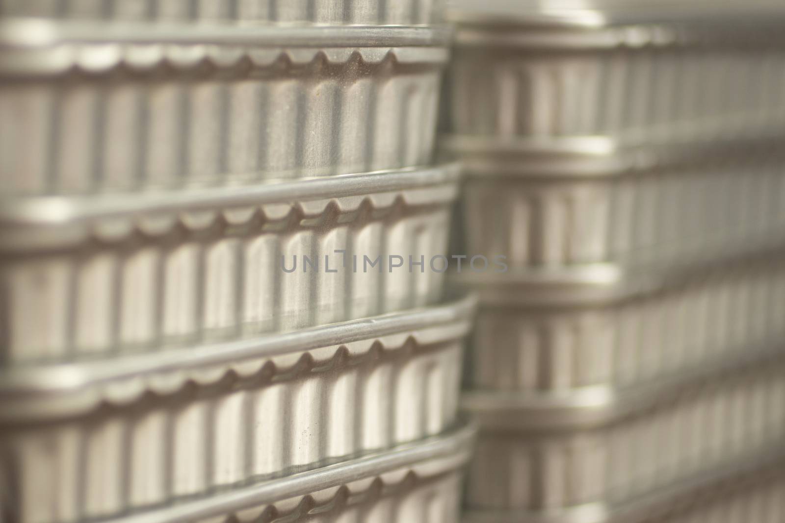 Color photo of grey metal aluminium cans of tinned sardine fish tins stacked up with shallow depth of focus. 