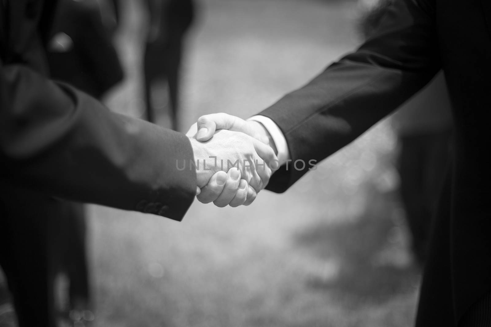 Men shaking hands in wedding reception party black and white photo.