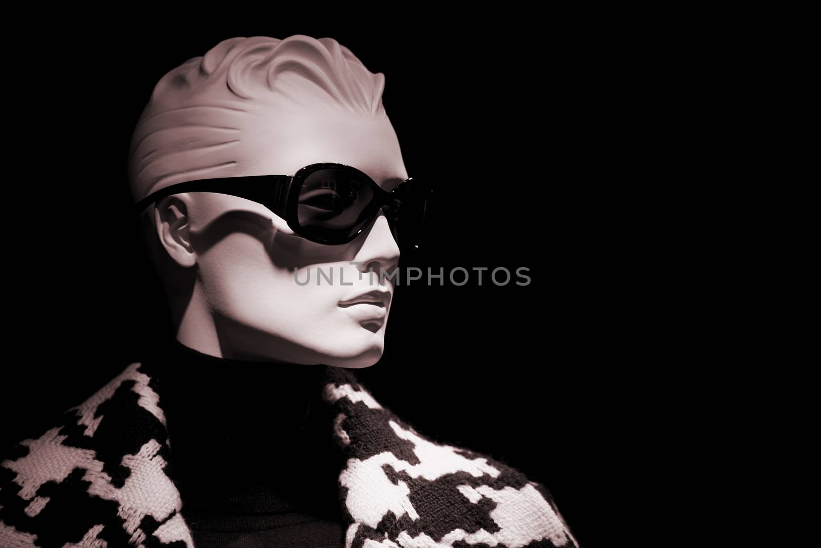 Shop dummy store mannequin female head with plastic hair wearing sunglasses on plain black background. 