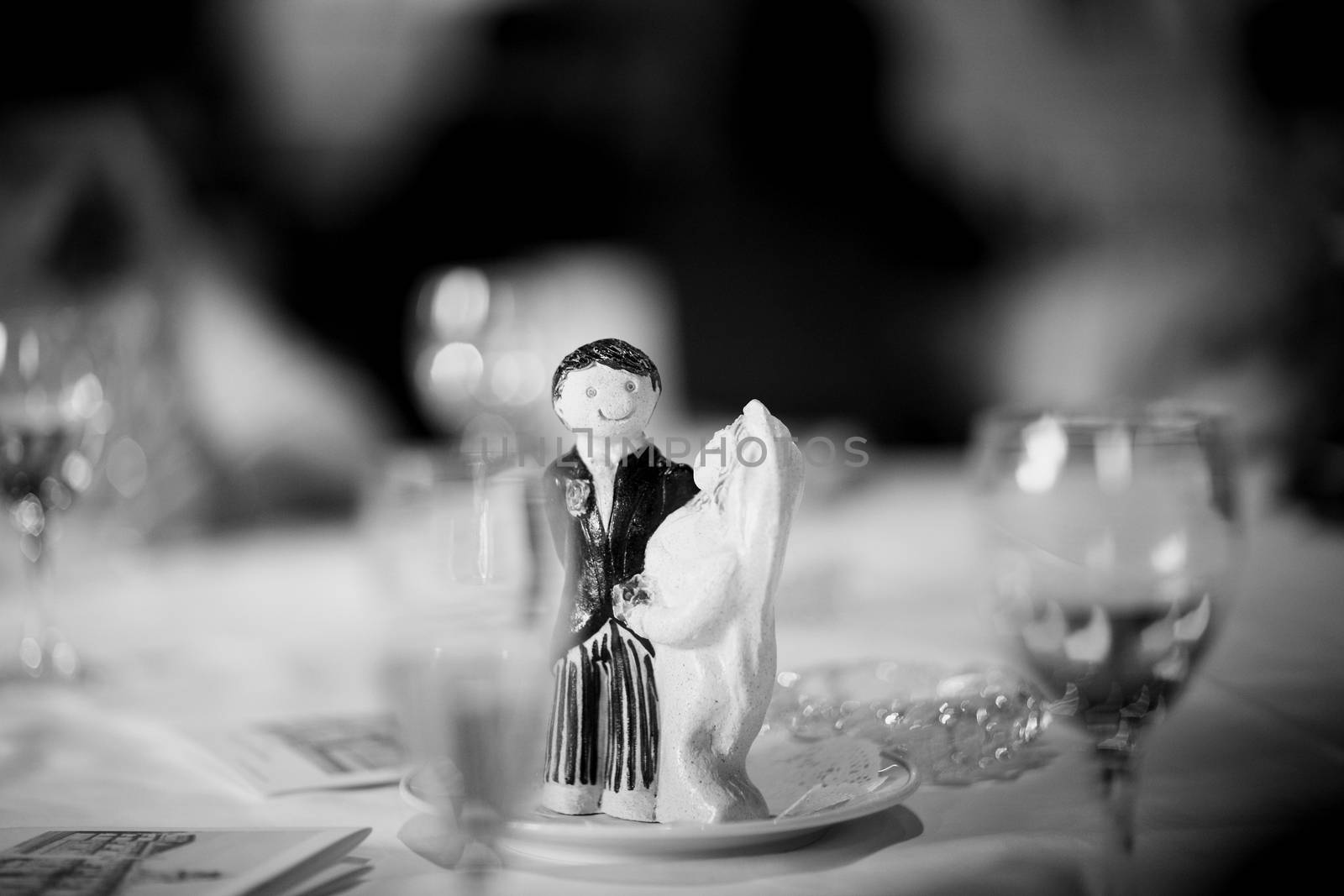 Wedding cake topper figurine bridegroom bride on wedding reception marriage banquet table black and white photo.