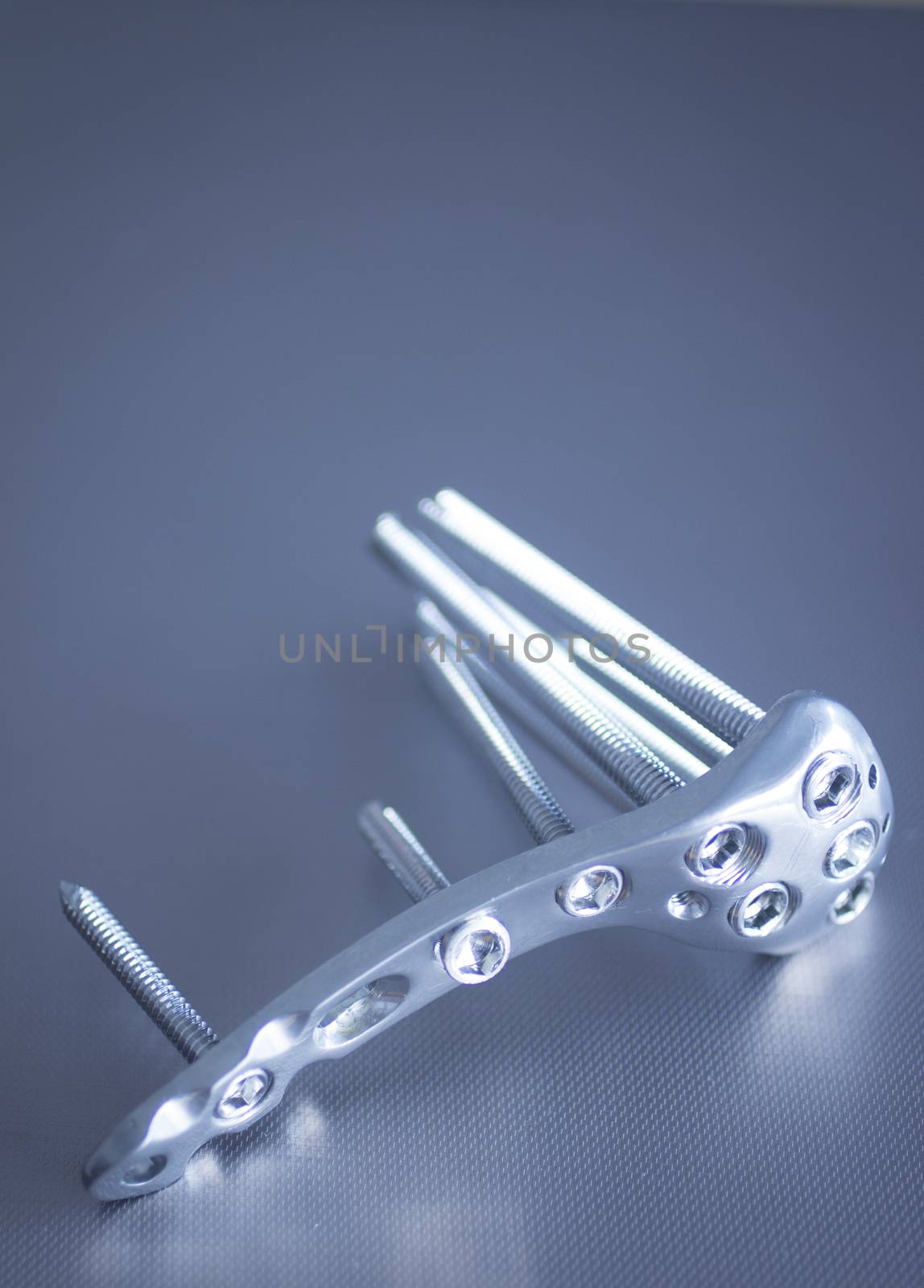 Trauma and orthopedic surgery metal implant with screws with reflection and bokeh light effect. Still life color digital photo with copy space. 