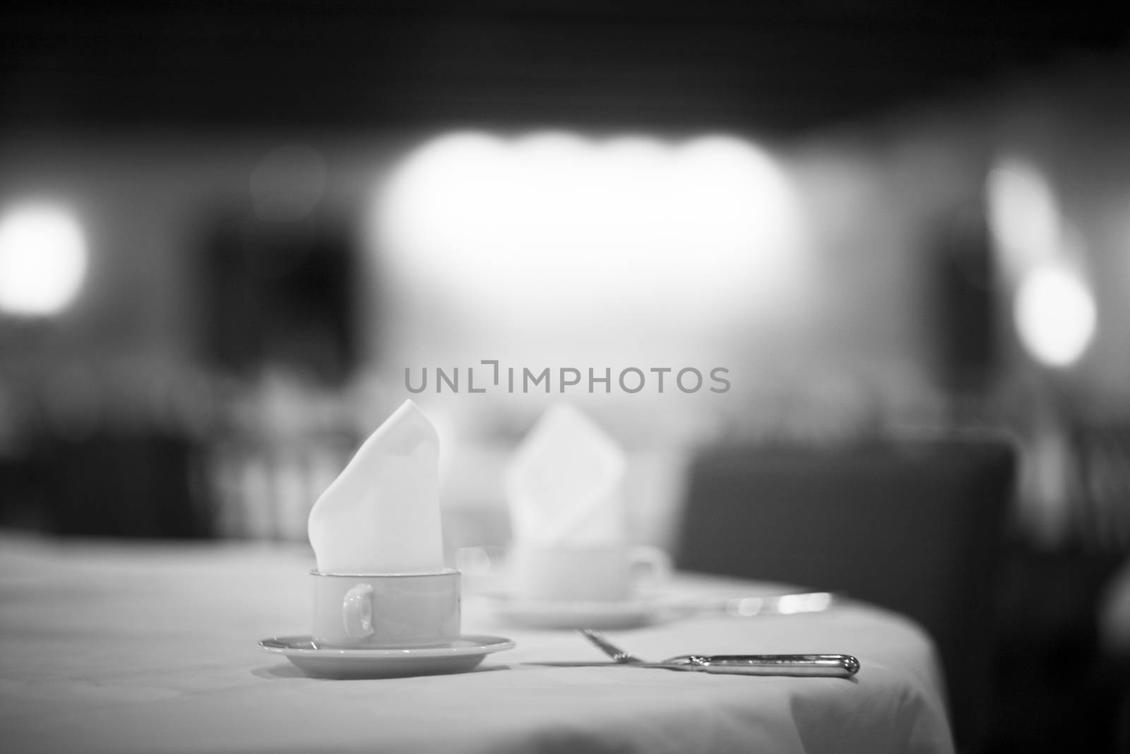 Coffee tea cup on wedding marriage reception banquet table with saucer, serviette and cutlery black and white photo. 