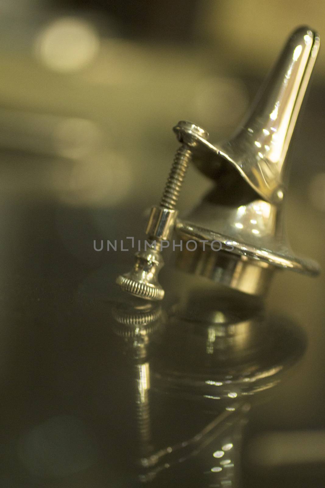 Traumatology and orthopedic injury surgery metal implant with screw with reflection and bokeh light effect. Still life color digital photo in brown tones. 