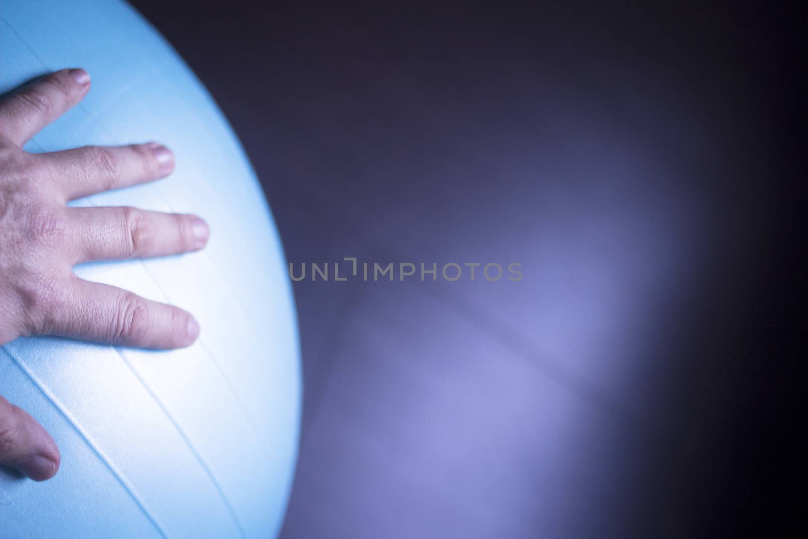 Blue pilates gym aerobics exercise ball in gymnasium and hand of man.