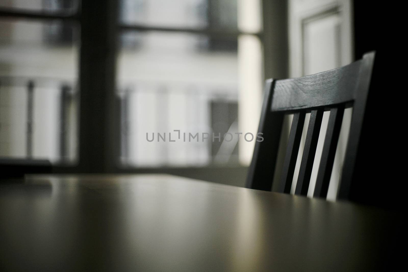 Table and wooden chair in room with window by edwardolive