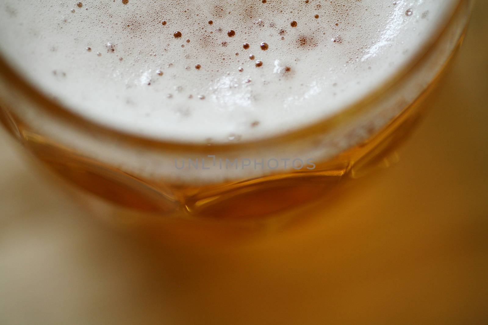 Studio isolated shot of traditional English style pint glass of lager beer in closeup macro color digital photo with focus on head foam shot from above. 