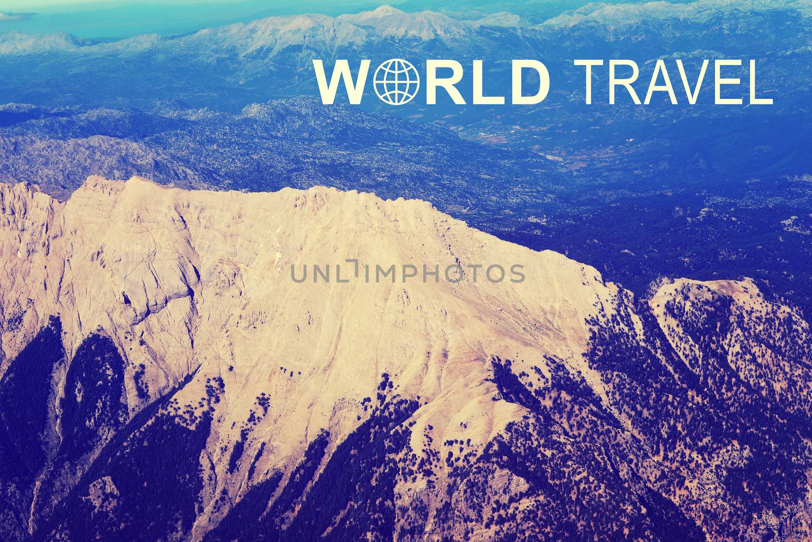 Aerial view of mountainous terrain with high ridge. Iinscription World Travel and related symbol
