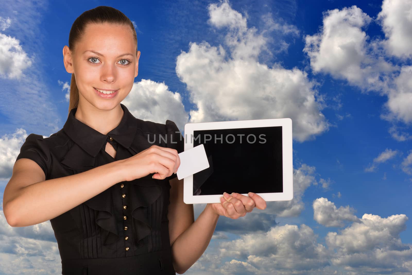 Beautiful businesswoman holding tablet PC. Blue sky and clouds as backdrop by cherezoff