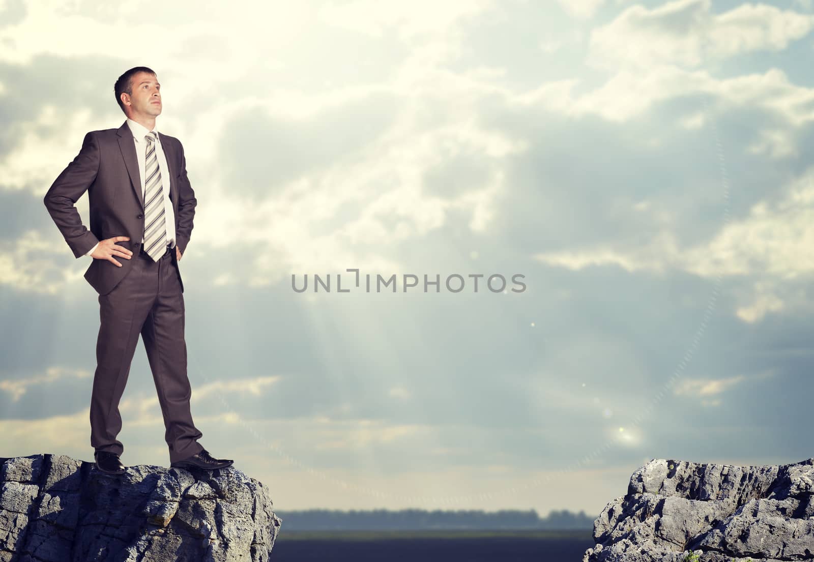 Businessman standing on the edge of rock gap by cherezoff