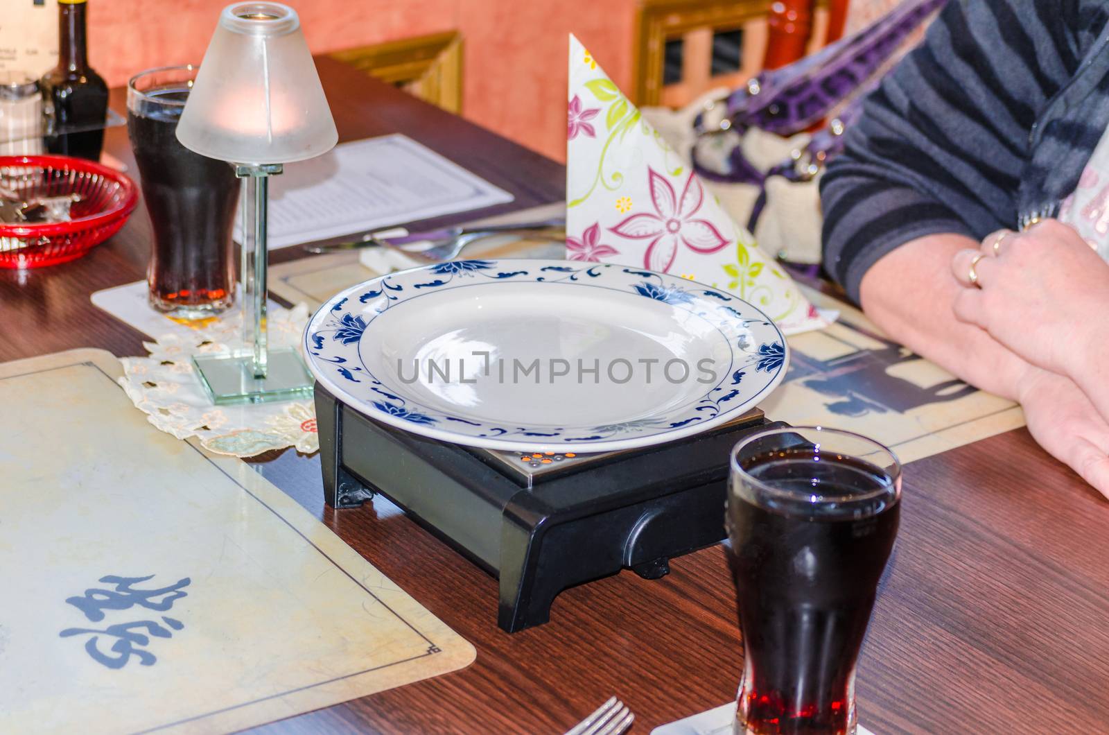 Chinese food, table decorations, plates with hot plate, candle and drinks.