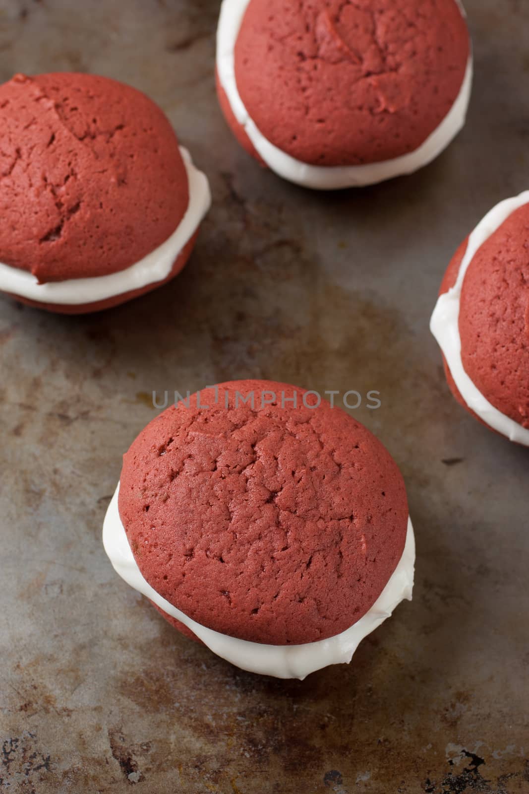 A red velvet whoopie pie with a peppermint cream cheese filling on a metal surface.