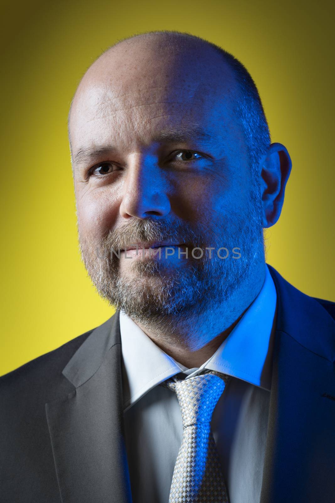 Businessman blue illuminated in dark suit and tie against yellow background