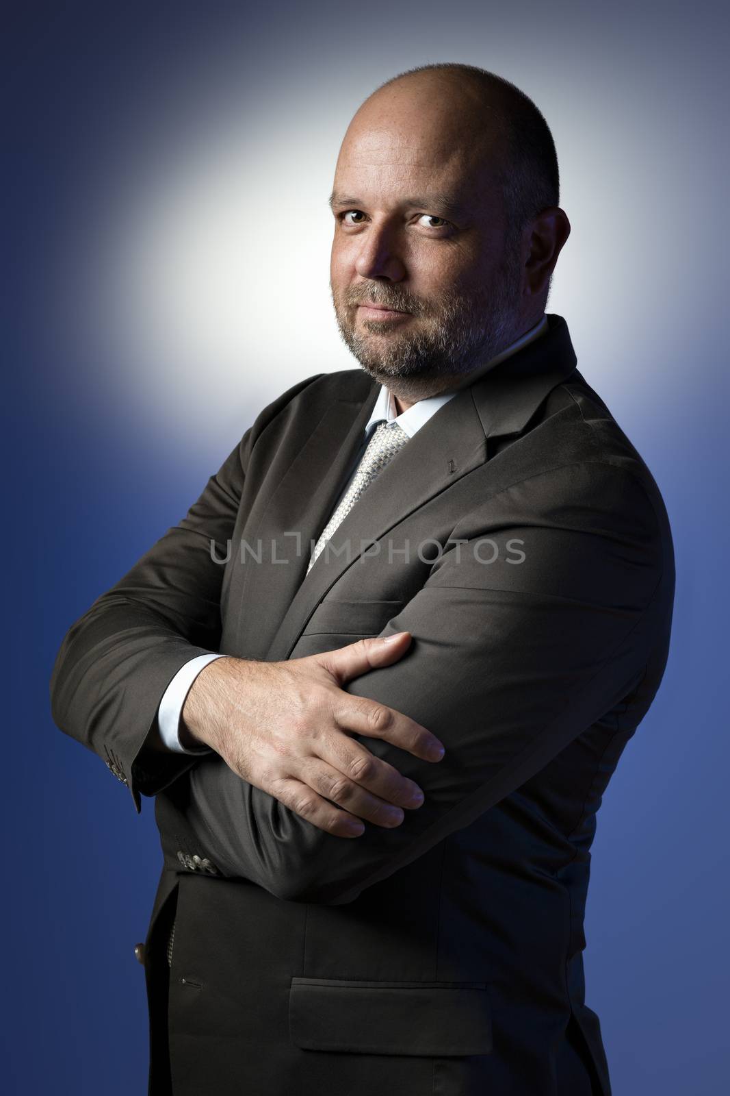 Serious businessman in dark suit and tie in front of blue background