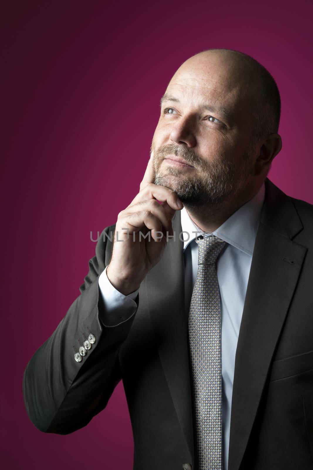 Reflective businessman in dark suit and tie against magenta background