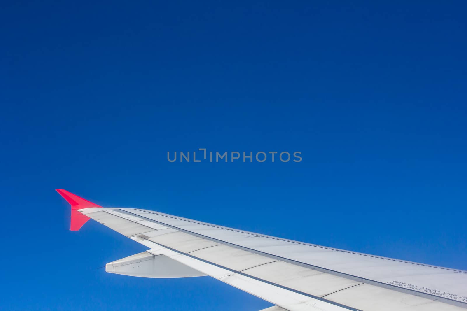 Wing airplane flying above clouds looking at the sky from the window, using air transport to travel.