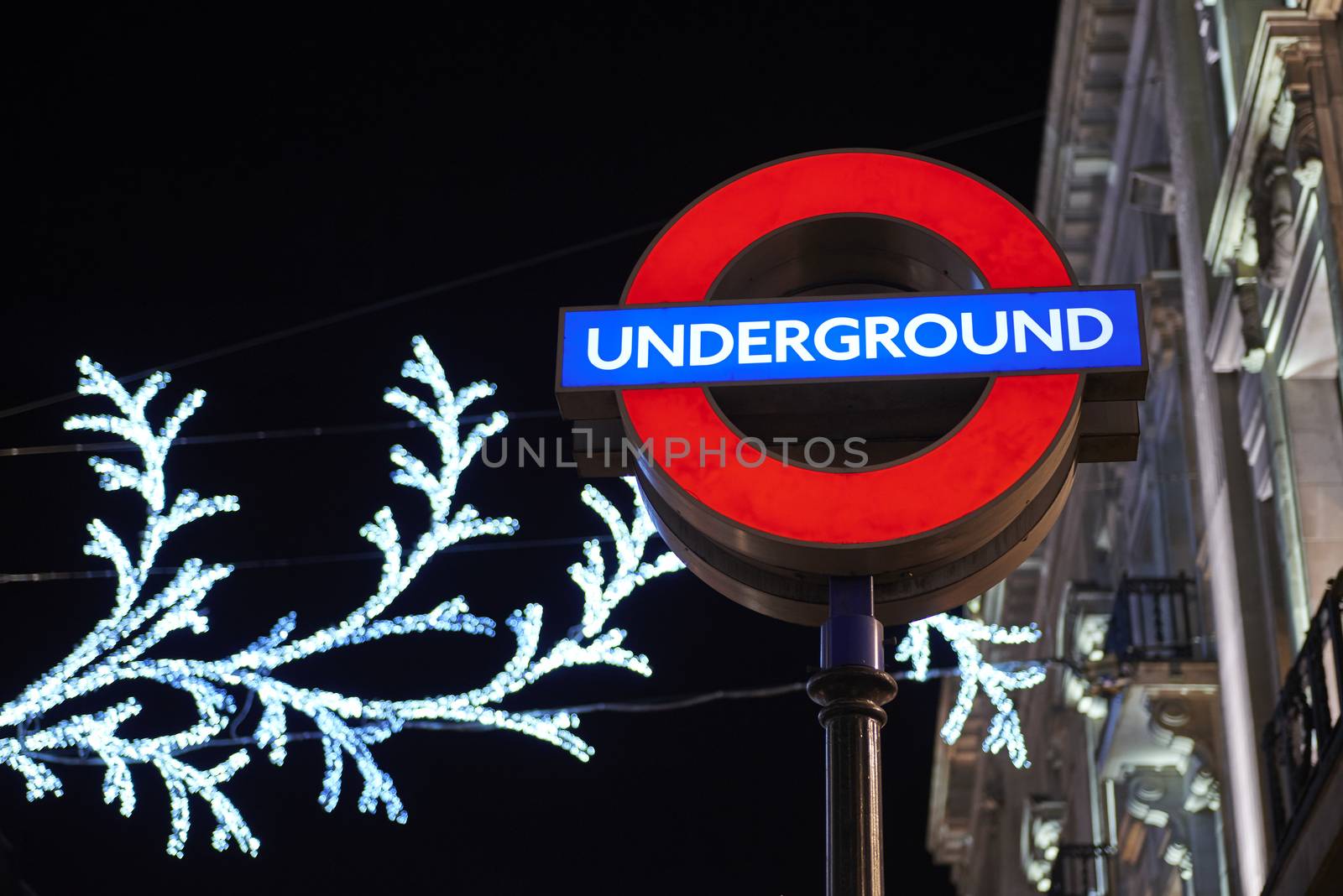LONDON, UK - DECEMBER 20: Nighttime shot of London underground entrance sign with Christmas lights in the background. December 20, 2014 in London.