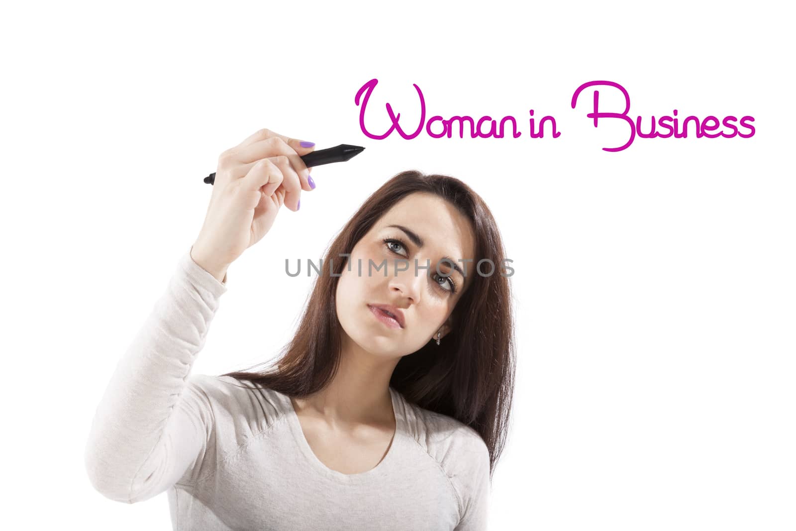 Beautiful girl writing with pink marker pen on virtual screen the phrase woman in business. Emancipation and femininity in business.