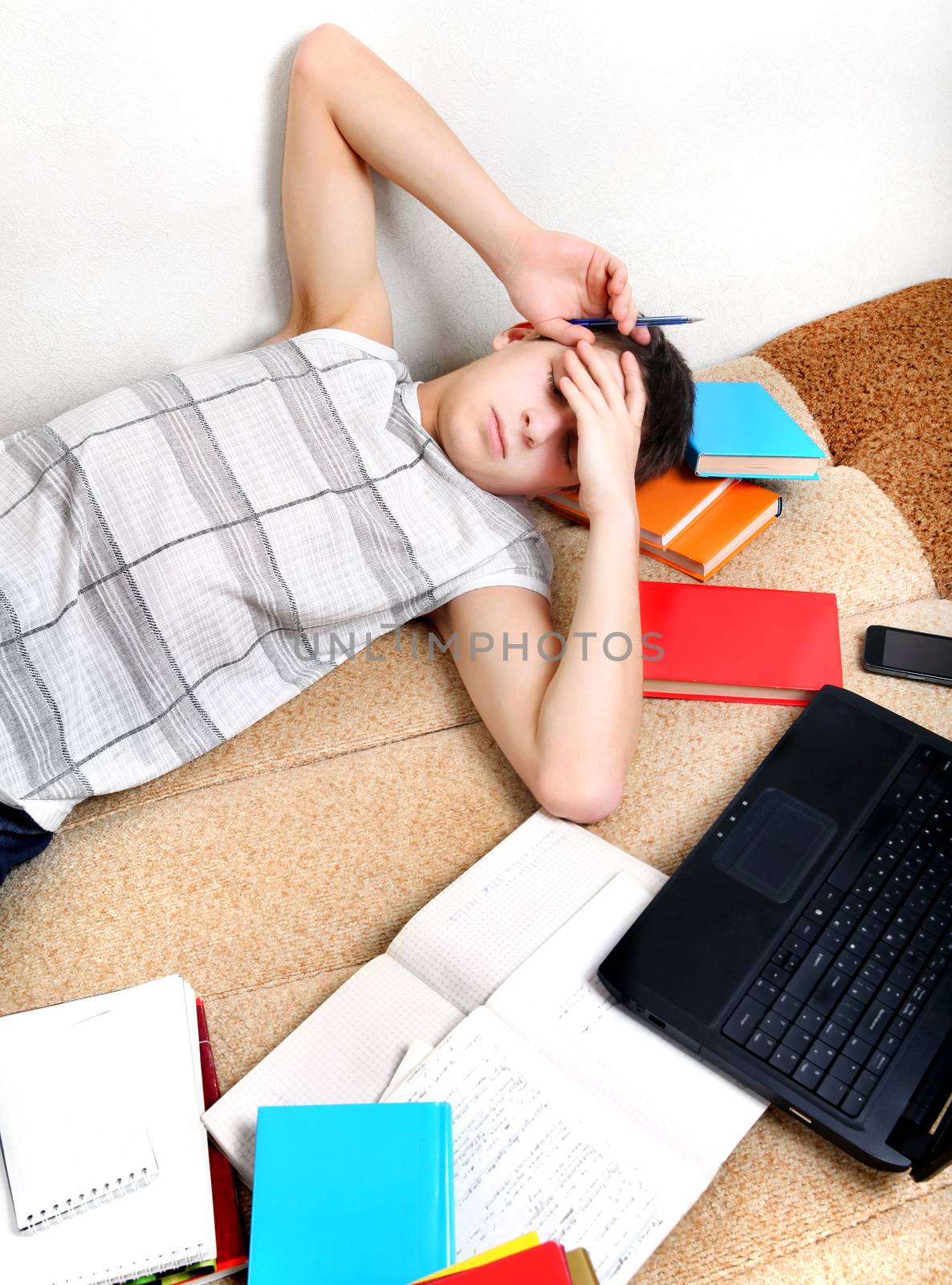 Tired Teenager on the Sofa with the Books at the Home