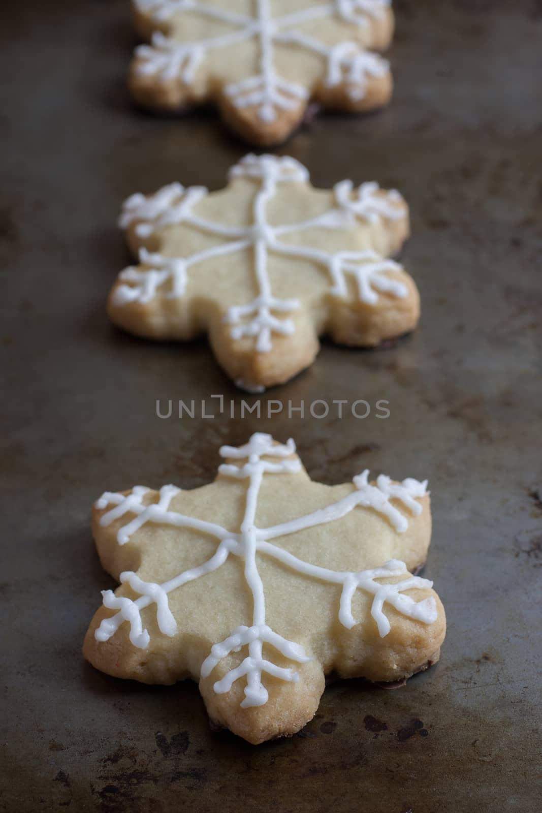 Snowflake shaped shortbreat cookies with chocolate dipped bottoms and icing on top.