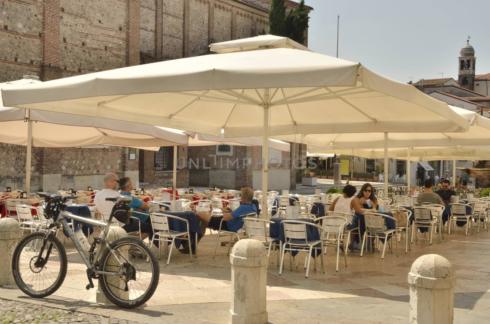 Some people in a outdoor restaurant  in the historical part of the city of Bassano del Grappa, Northern Italy