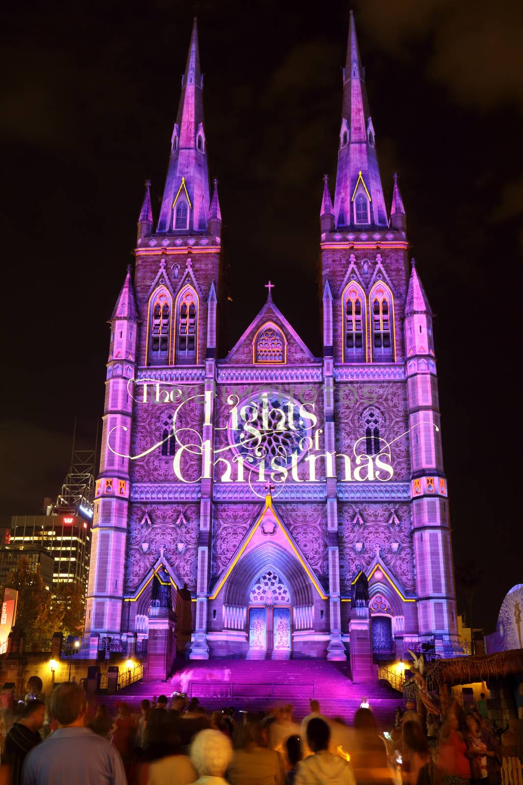 SYDNEY, AUSTRALIA - DECEMBER 23, 2014; Crowds of people on the forecourt of St Mary's Cathedral Sydney CBD watch and enjoy the Christmas lights display.  One of the many visions projected on the church building sandstone facade at Christmas time.