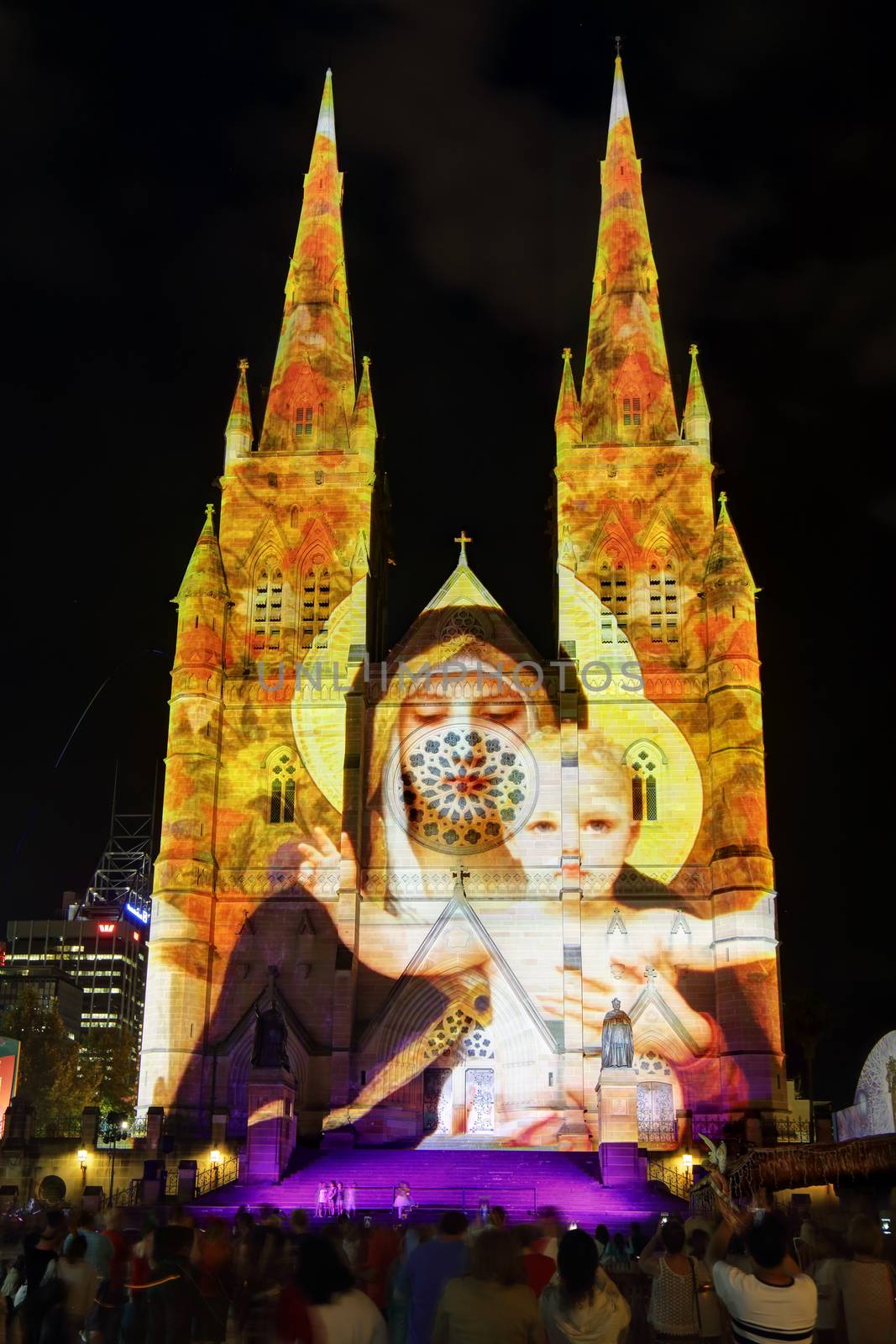 SYDNEY, AUSTRALIA - DECEMBER 23, 2014; Crowds of people on the forecourt of St Mary's Cathedral Sydney CBD watch and enjoy the Christmas lights display.  Madonna and Child one of the many visions on display on the church building sandstone facade at Christmas time.