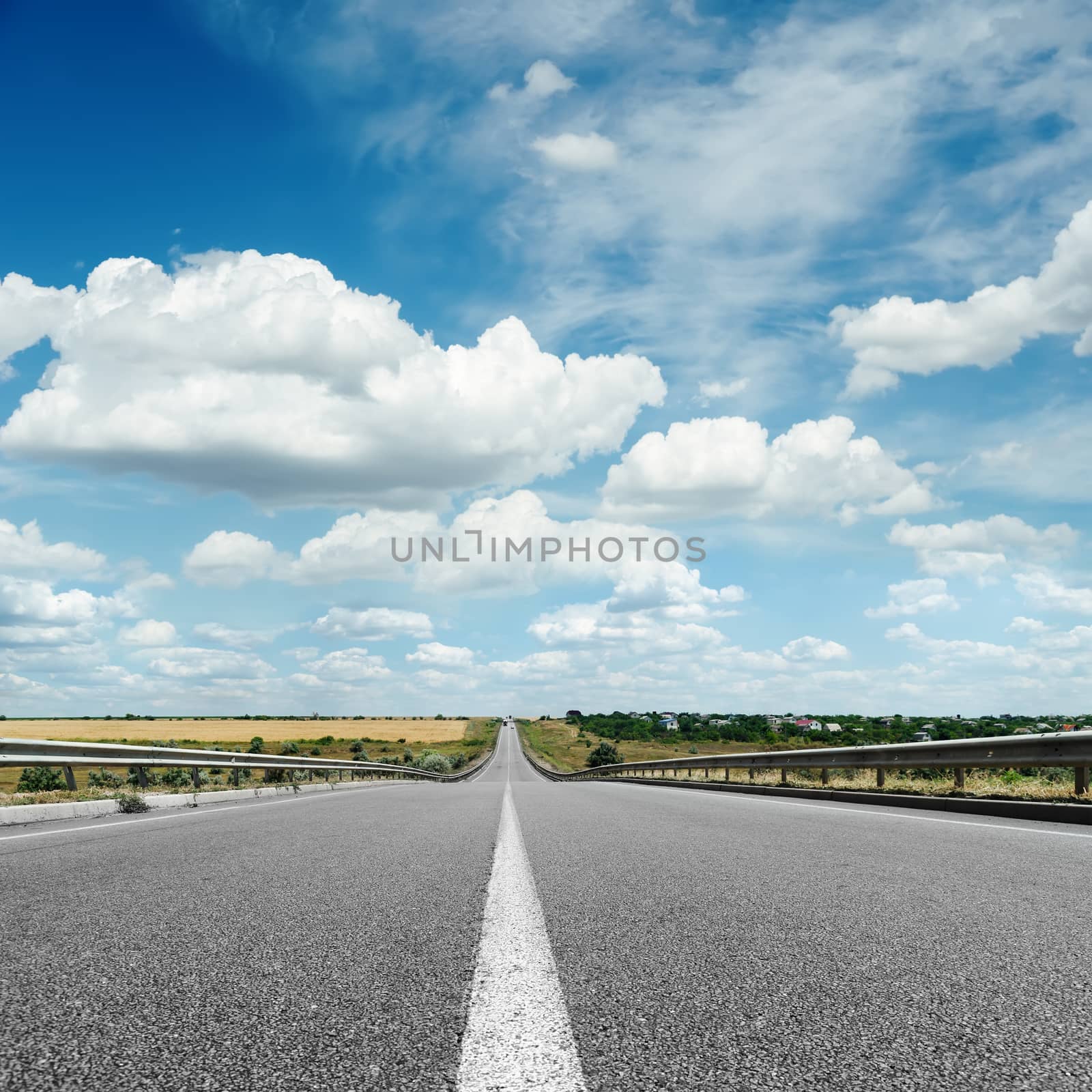 asphalt road with white line on center close up under cloudy sky by mycola