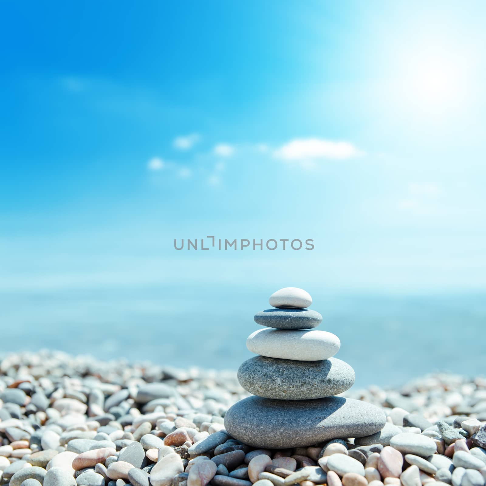 zen-like stones on beach and sun in sky by mycola