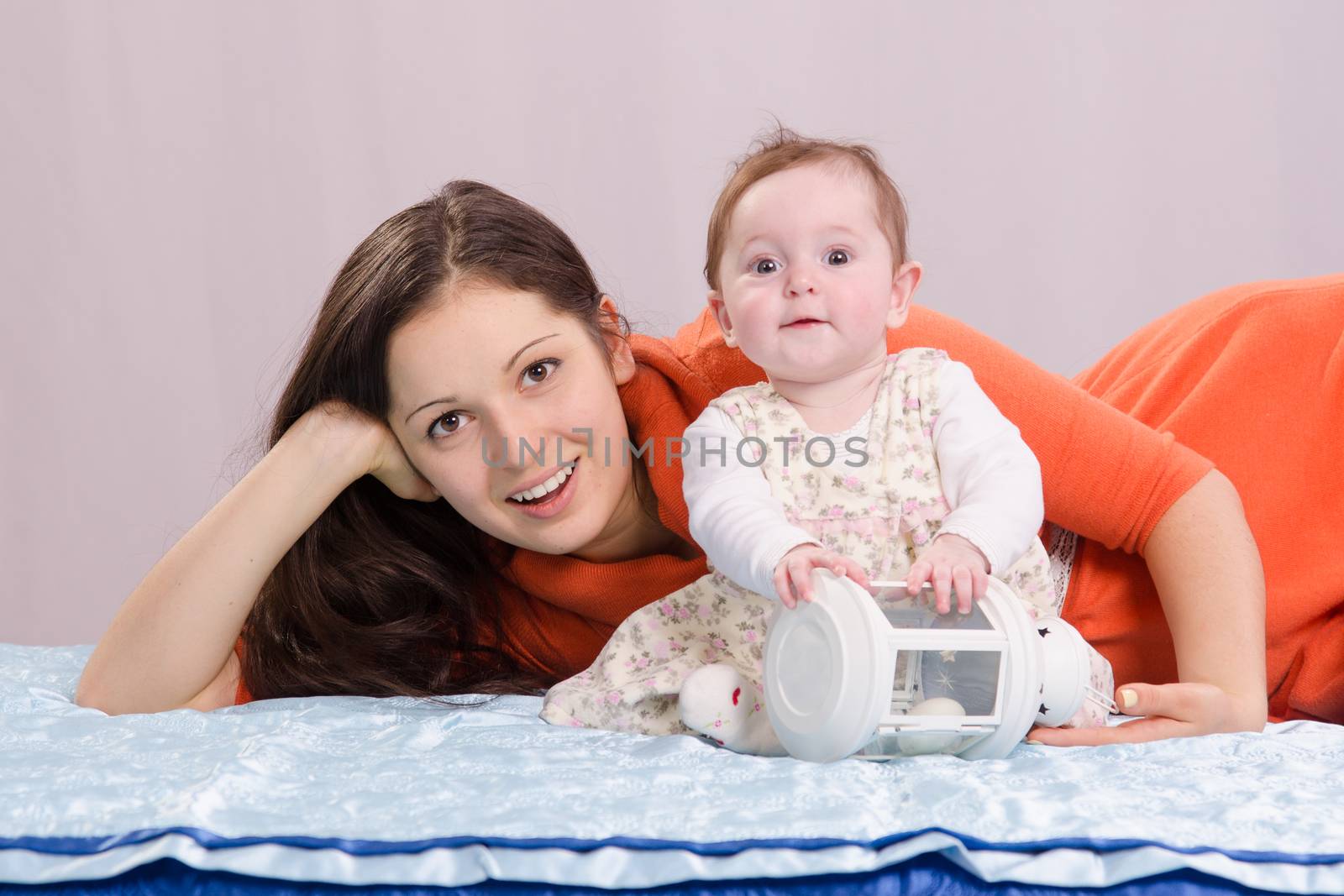 Mom and six-month daughter happily lie on the couch