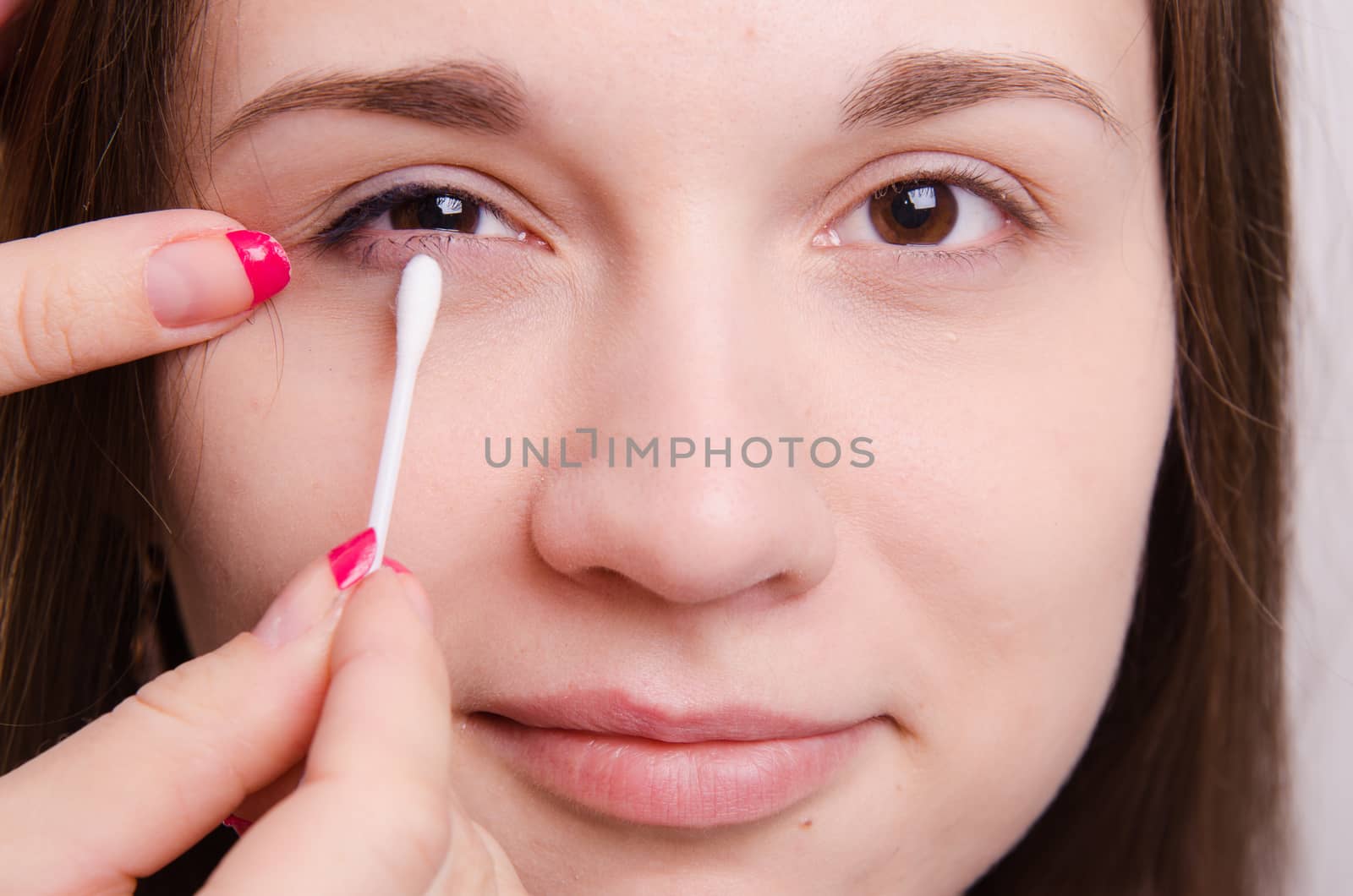 Makeup artist paints the eyelids of a beautiful young girl in the makeup
