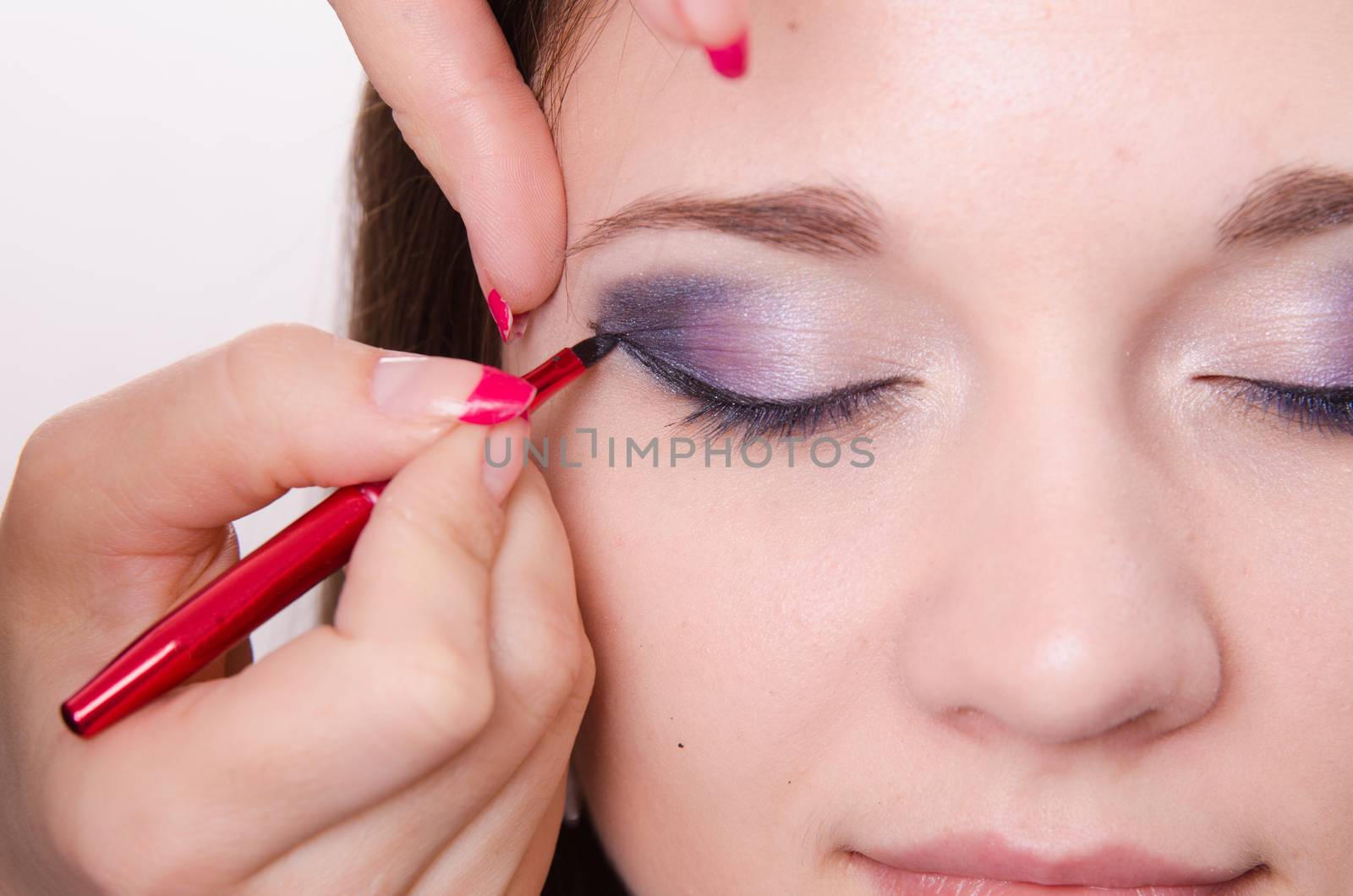 Makeup artist draws arrows beautiful young girl in the makeup