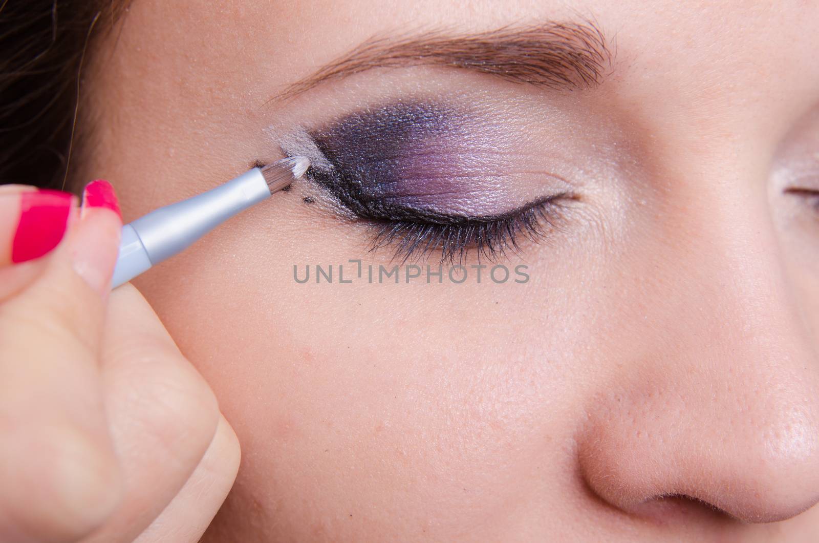 Makeup artist draws arrows beautiful young girl in the makeup