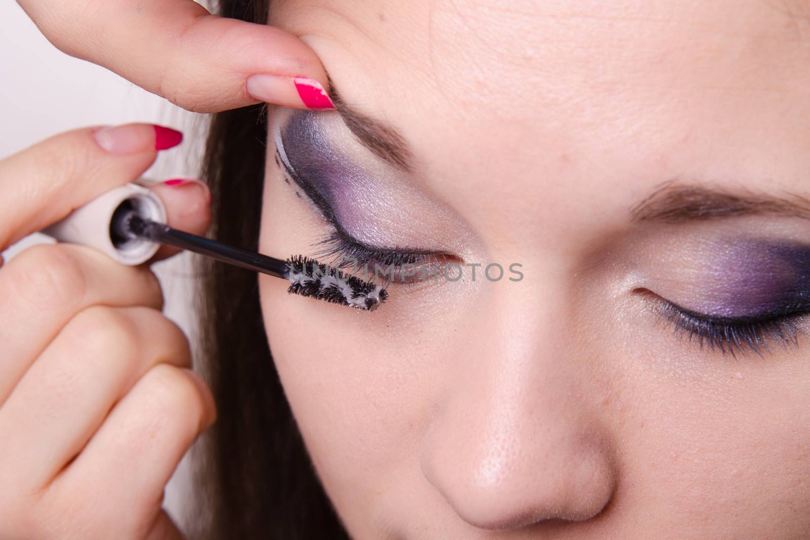 Makeup artist paints eyelashes of a beautiful young girl in the makeup