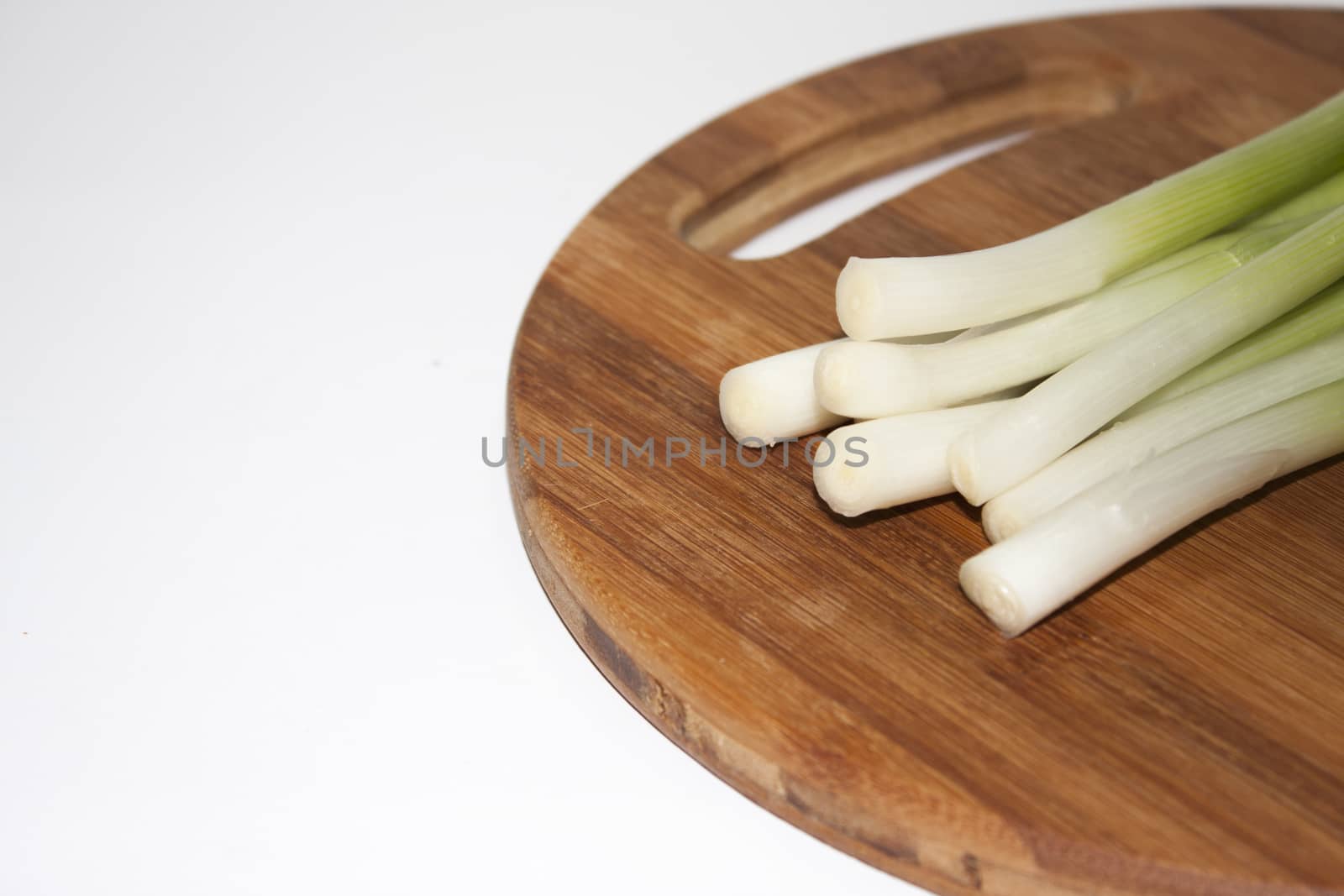 Young onions on the kitchen wooden board.