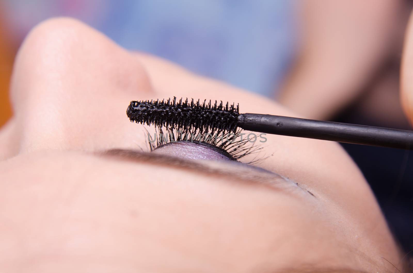 Makeup artist paints eyelashes of a beautiful young girl in the makeup
