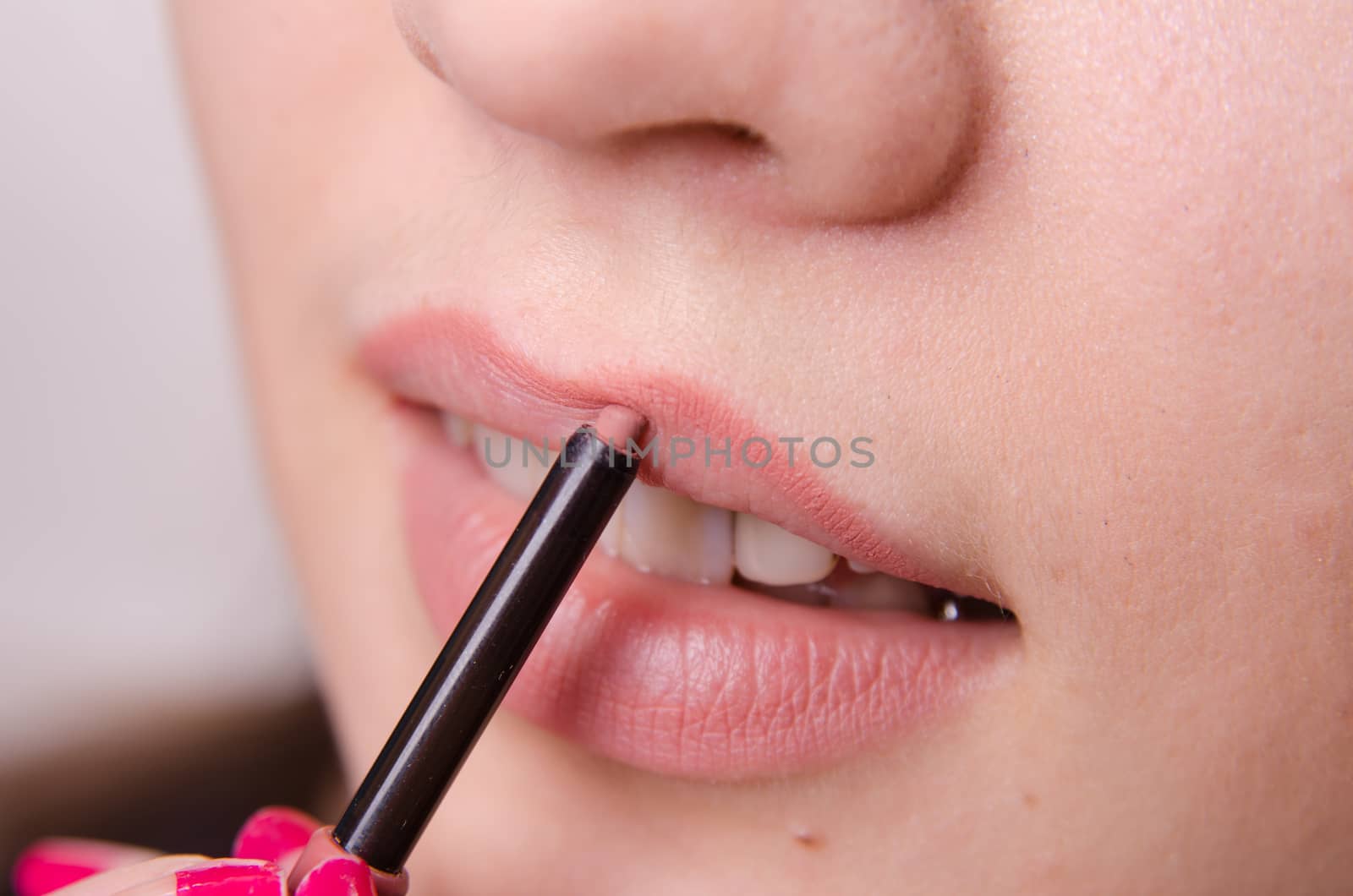 Makeup artist paints her lips a beautiful young girl in the makeup