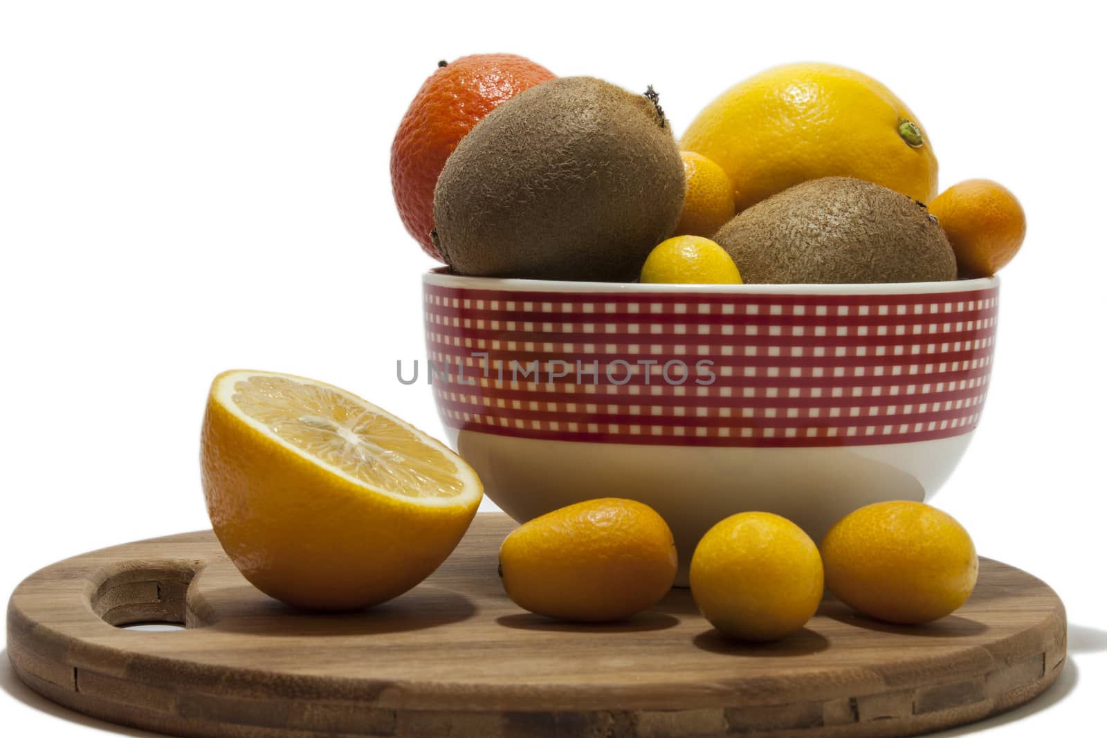Fruit arrangement in the bowl and on the kitchen wooden board. Lemon, kumquat, kiwi and tangerine in the bowl and on the kitchen wooden board.