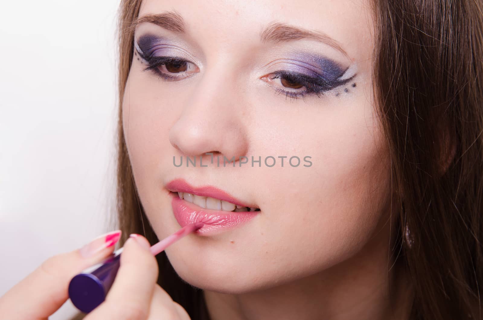 Makeup artist paints her lips a beautiful young girl in the makeup