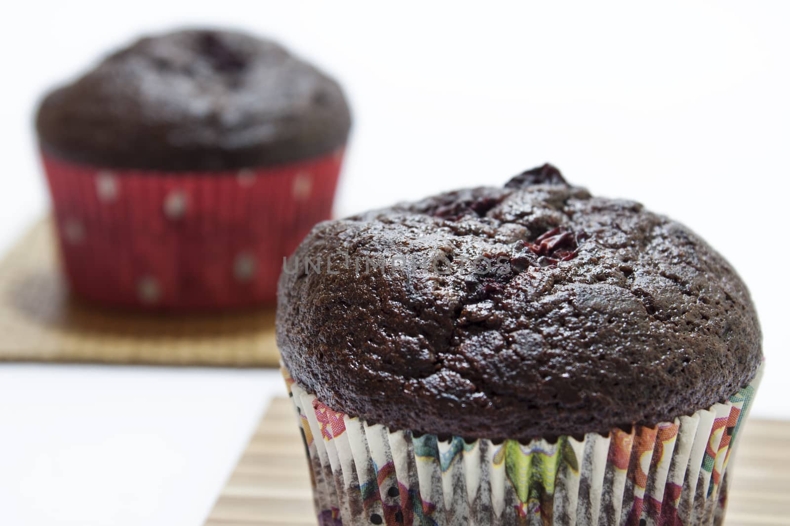 Chocolate muffins on a bamboo mat and white background.