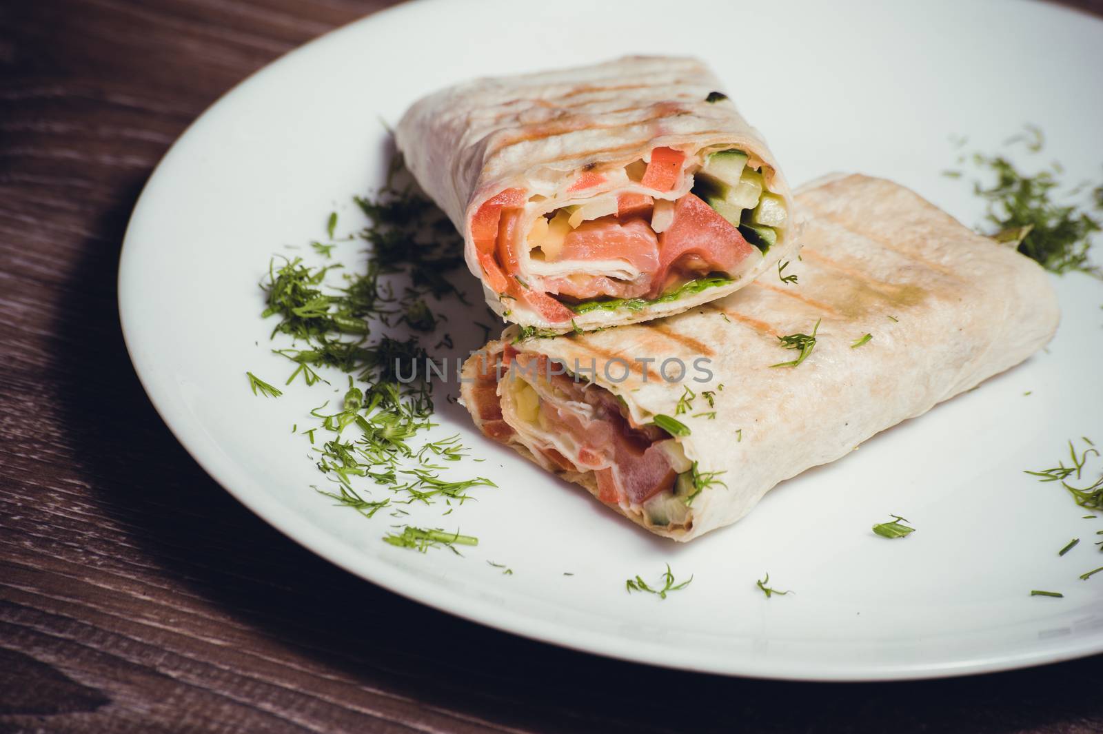 smoked salmon wrap with vegetables on white plate 