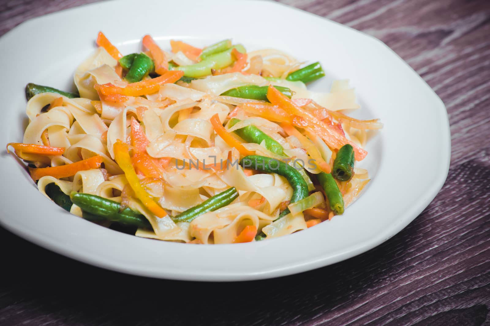 vegetarian pasta with carrot, zucchini on white plate 