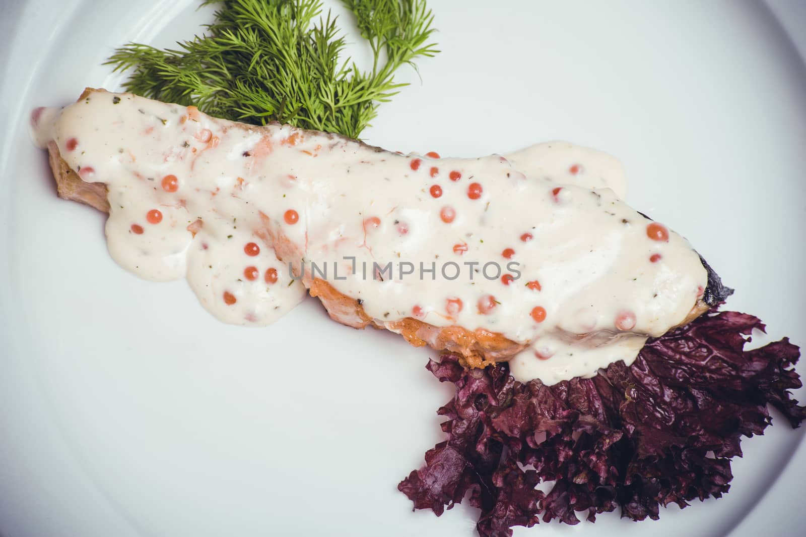 salmon fillet with caviar cream sauce on white plate 