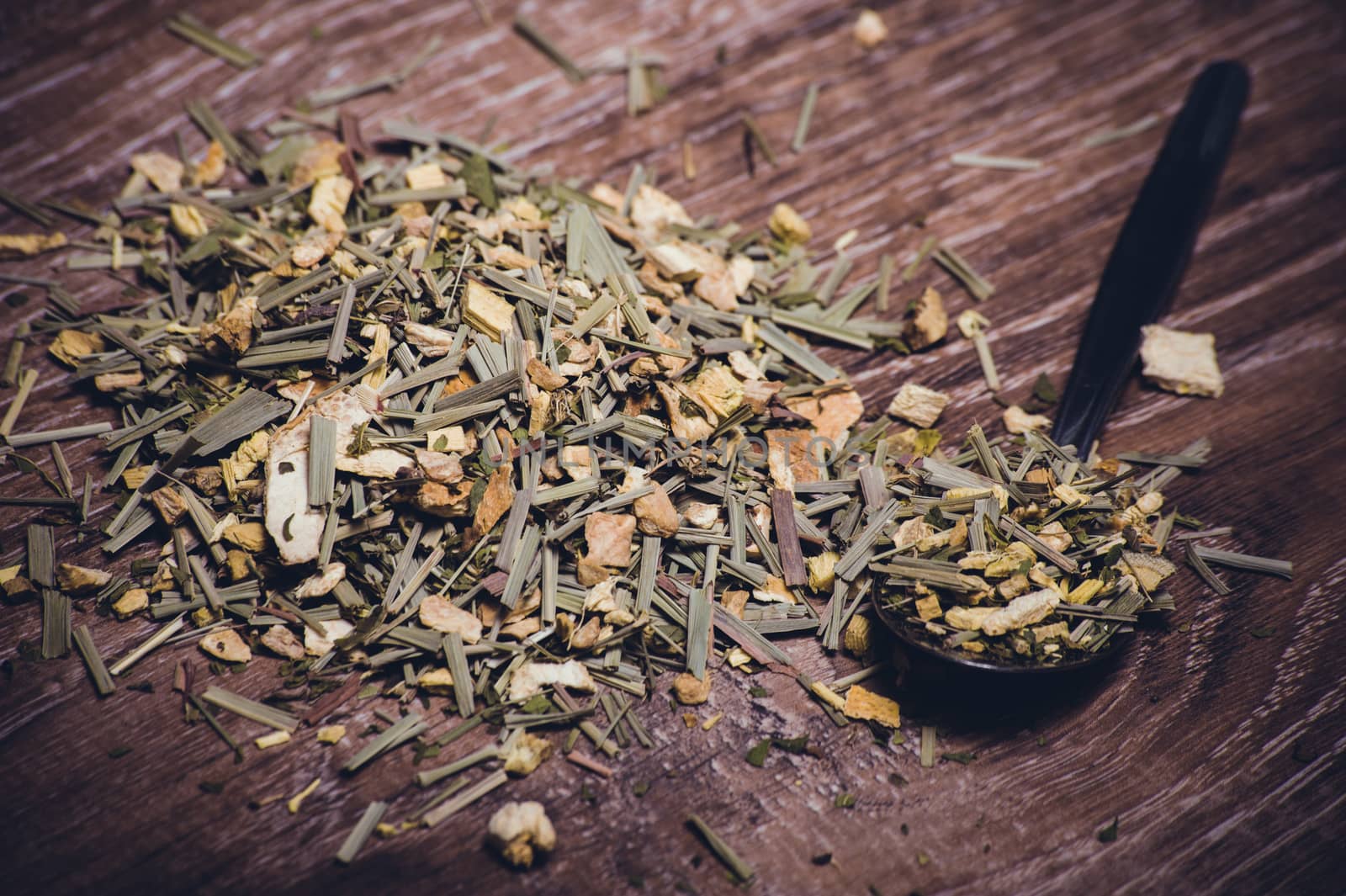 dried herbal tea on spoon on wooden background 