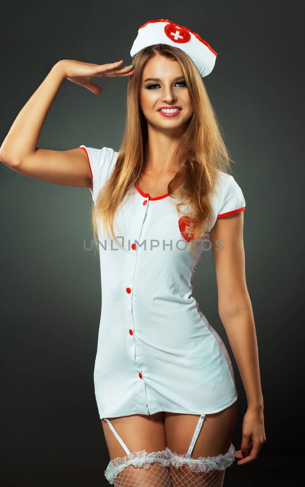 Young and beautiful dancer in nurse costume posing on studio background